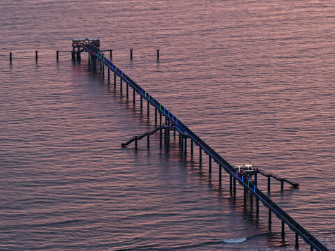 Cox's Bazar, Chittagong Division, Bangladesh - 08 April 2026: Aerial view of the long pier extending into the sea at dusk, illuminated by colorful lights along the walkway.