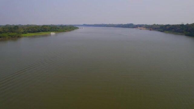 Aerial view of the Ucayali River flowing through the Amazon rainforest, with lush green banks and calm water in Pucallpa, Ucayali, Peru.