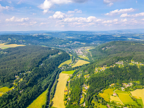 Aerial view of the Jizera river winding through the lush green forests and fields of the Bohemian Paradise near Mala Skala, Liberec Region, Czechia.
