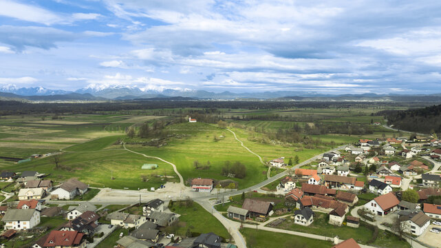 Aerial view of the church of Sv. Ana on a grassy hill overlooking the village of Preserje, surrounded by green fields and meadows in Preserje, Ljubljana, Slovenia.