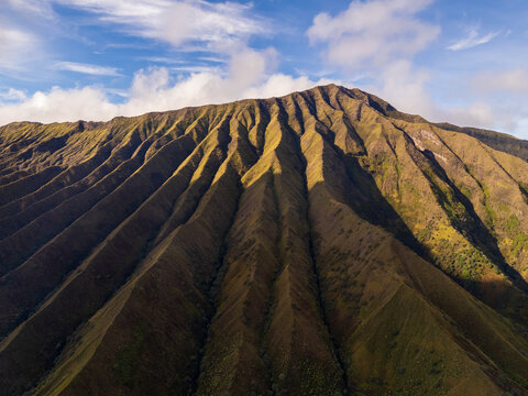 Aerial view of the dramatic ridged volcanic slopes of Mount Bromo under a clear blue sky in Tosari, East Java, Indonesia.
