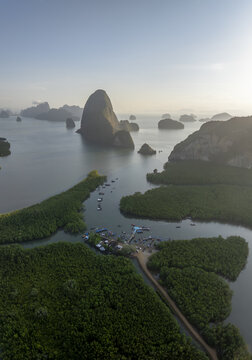 Aerial view of Hin Rom Pier surrounded by lush mangrove forests and limestone karst formations in the calm bay of Tambon Khlong Khian, Chang Wat Phang-nga, Thailand.