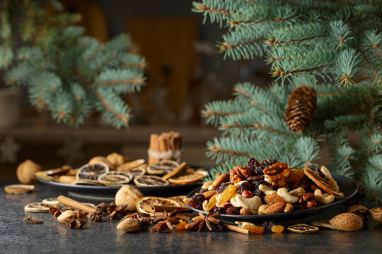 Christmas spices, various nuts, raisins, and dry citrus slices on a kitchen table.