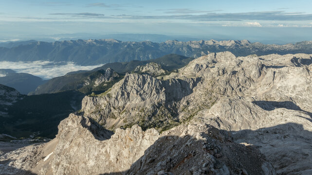 Aerial view of the rugged limestone peaks of Triglav National Park with clouds settling in the deep valleys of the Julian Alps in Bohinjsko jezero, Slovenia, Slovenia.