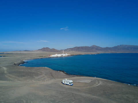 09 January 2019: Aerial view of a camper van parked on a coastal cliff overlooking the blue sea with mountains in the background.