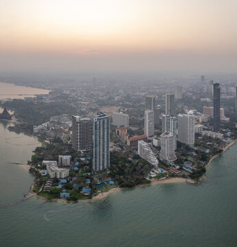 Aerial view of the coastal skyline featuring modern high-rise buildings, hotels, and resorts along the shoreline during sunset in Pattaya City, Chon Buri, Thailand.