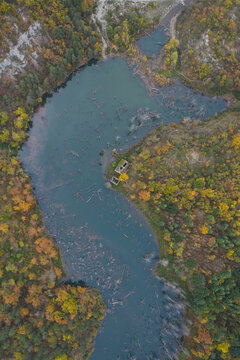 Aerial view of Lago di Poggio Baldi surrounded by dense autumn forest with colorful foliage and submerged tree trunks in the water in Santa Sofia, Emilia-Romagna, Italy.