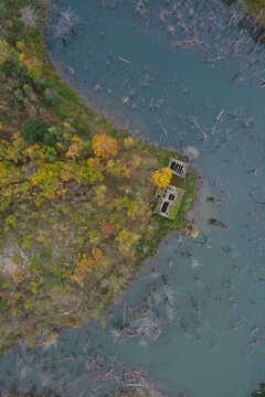 Aerial view of the submerged ruins of Lago di Poggio Baldi surrounded by autumn forest and dead trees in the water in Santa Sofia, Emilia-Romagna, Italy.