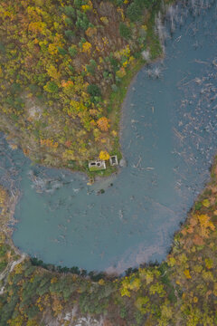 Aerial view of Lago di Poggio Baldi surrounded by dense autumn forest with colorful foliage and submerged tree trunks in the water in Santa Sofia, Emilia-Romagna, Italy.