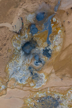 Aerial view of the Hverir geothermal area featuring bubbling mud pots, colorful mineral deposits, and visitors on wooden paths in the barren landscape of Reykjahlid, Thingeyjarsveit, Iceland.