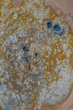 Aerial view of Hverir geothermal area featuring vibrant orange and yellow mineral deposits, bubbling mud pots, and steaming vents in Reykjahlid, Thingeyjarsveit, Iceland.