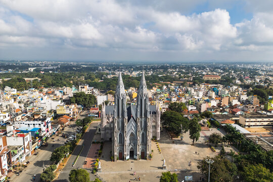 Mysuru, India - 04 November 2022: Aerial view of St. Philomena's Cathedral with its twin spires surrounded by the urban landscape of Mysuru under a cloudy sky.