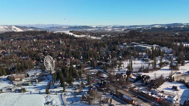 Aerial view of Zakopane in the Tatra Mountains, Poland, with snow-covered chalets, pine forests and roads under a clear blue winter sky in Lesser Poland Voivodeship.