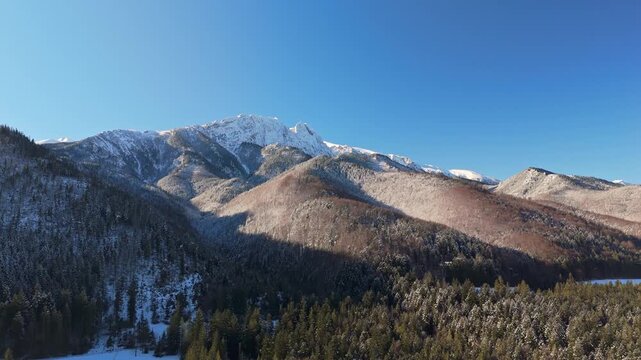 Aerial view of the snow-covered Tatra Mountains near Zakopane, Poland, with alpine ridges, forested valleys and clear blue winter sky in the High Tatras natural landscape.