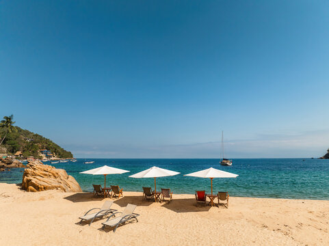 Aerial view of Yelapa Beach with white sand, lounge chairs, and umbrellas under a clear blue sky in Yelapa, Jalisco, Mexico.