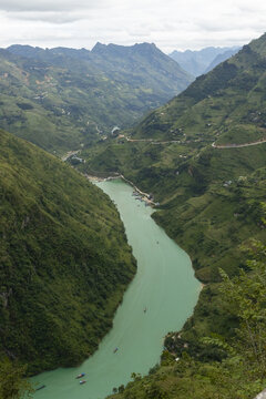 View of the Nho Que River winding through the dramatic limestone mountains and lush green terraced slopes of the Ha Giang Loop in Dong Van, Tuyen Quang, Vietnam.