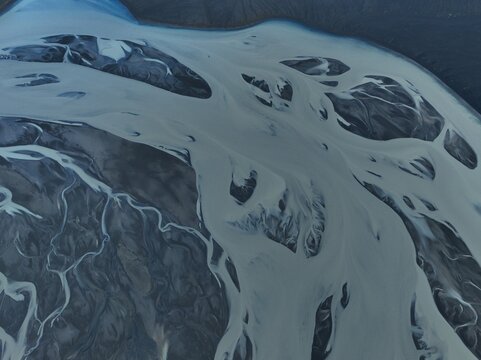 Aerial view of the intricate braided river patterns of Skyggnisvatn, with glacial sediment and dark volcanic sand banks in Hella, Rangarthing ytra, Iceland.