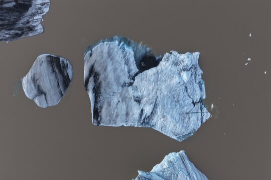 Aerial view of iceberg fragments floating in murky glacial water in Svinafell, Iceland.