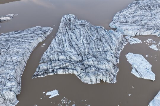 Aerial view of icebergs floating in the brown water of a glacial lagoon near Falljokull glacier in Svinafell, Sveitarfelagid Hornaf, Iceland.