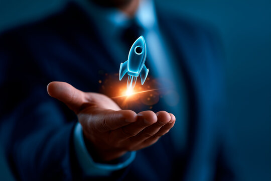 Businessman holding glowing digital rocket hologram over extended hand for startup growth