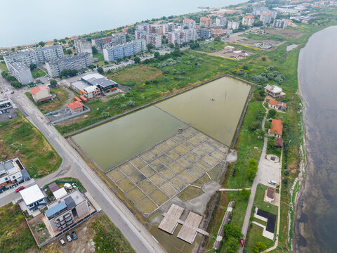 Aerial view of the Salt Museum in Pomorie, featuring historic salt pans, shallow water basins, and surrounding urban infrastructure near the Black Sea coast in Pomorie, Burgas, Bulgaria.