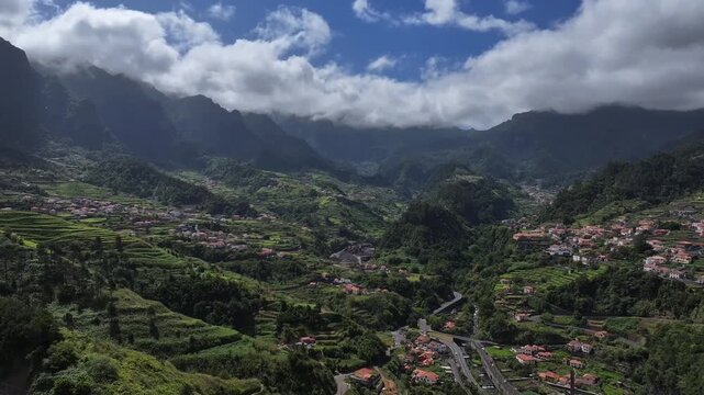 Aerial view of the Chapel of Nossa Senhora de Fatima perched on a hill surrounded by lush green mountains and terraced slopes in the valley of Sao Vicente, Madeira.