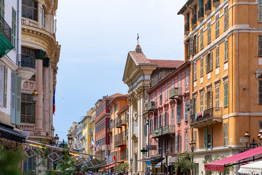 View of the historic street in Old Nice with colorful Mediterranean buildings and the facade of a church under a clear sky in Nice, Provence-Alpes-Cote d'Azur, France.