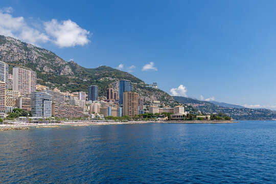 View of the coastal skyline of Monaco City featuring modern high-rise buildings set against the mountains and the Mediterranean Sea in Monaco City, Monaco.
