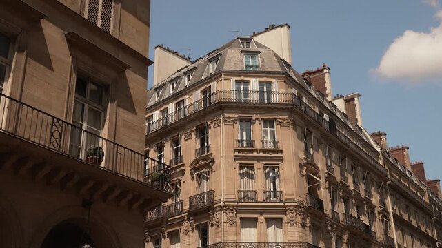 Ornate balconies on a Paris limestone facade under summer clouds