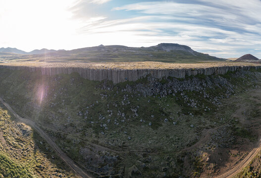 Aerial view of Gerduberg Cliffs featuring hexagonal basalt columns rising above the grassy landscape under a bright sky in Raudhamelur, Eyja- og Miklaholtshr, Iceland.