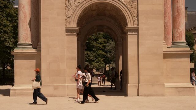 Visitors walking through a triumphal arch in central Paris