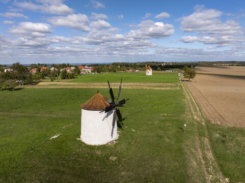 Aerial view of the historic Regi Szelmalom windmills set in green fields with a blue sky in Tes, Hungary.