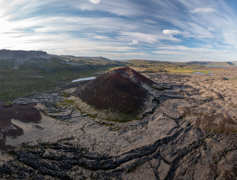 Aerial view of Ytri-Raudarmelskula volcanic crater surrounded by rugged lava fields and mossy terrain under a vast sky, Raudhamelur, Eyja- og Miklaholtshr, Iceland.