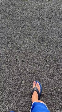 Person walking on asphalt road wearing blue flip flops