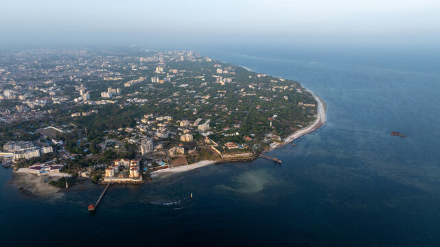 Aerial view of the coastal city of Mombasa, featuring urban development, lush greenery, and piers extending into the Indian Ocean in Mombasa, Mombasa County, Kenya.