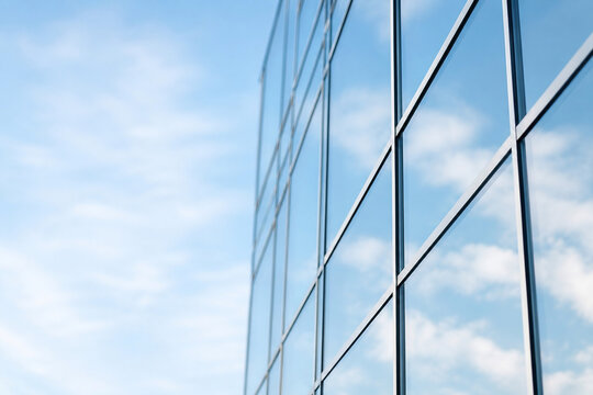 Moderne Glasfassade mit Spiegelung von Himmel und Wolken