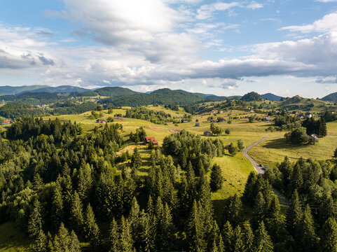 Aerial view of the rolling green hills and coniferous forests of the rural landscape in Sirnea, Brasov, Romania.