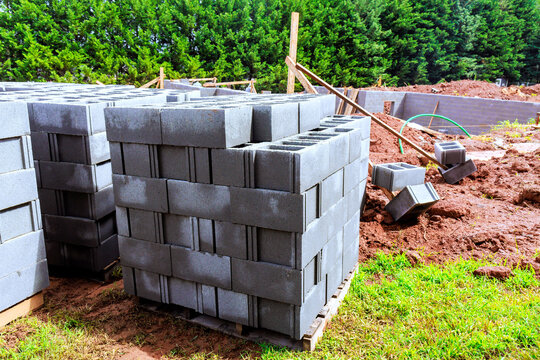 Cinder blocks are stacked on wooden pallet at construction site surrounded dirt.