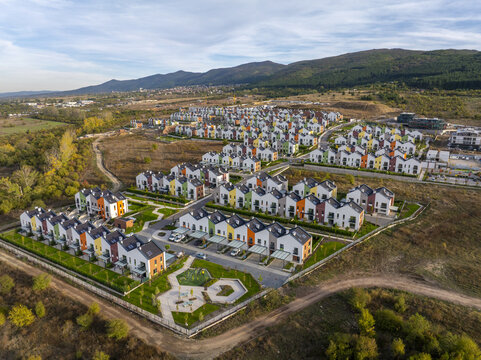 Aerial view of Residential Park Lozen featuring modern colorful houses with green lawns and paved streets set against a backdrop of rolling hills in Sofia, Sofia City Province, Bulgaria.
