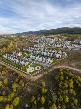 Aerial view of Residential Park Lozen featuring modern colorful houses, manicured green spaces, and paved roads nestled in a hilly landscape near Sofia, Sofia City Province, Bulgaria.