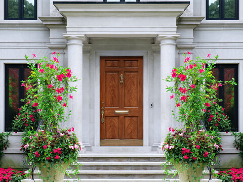 House entrance with stone columns and large potted flowering Mandevilla vines