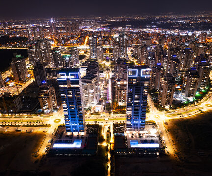 Aerial view of the illuminated skyline of Netanya at night, featuring modern high-rise towers, glowing windows, urban street lights, and swimming pools, Netanya, Center District, Israel.