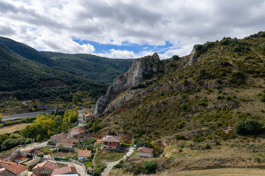 Aerial view of the rocky landscape and village featuring stone houses, rolling hills, and a highway winding through the valley under a cloudy sky in Ameyugo, Castile and Leon, Spain.