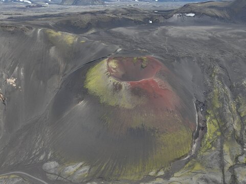 Aerial view of the vibrant red Raudaskal crater surrounded by dark volcanic ash and patches of green moss in Akureyri, Rangarthing ytra, Iceland.