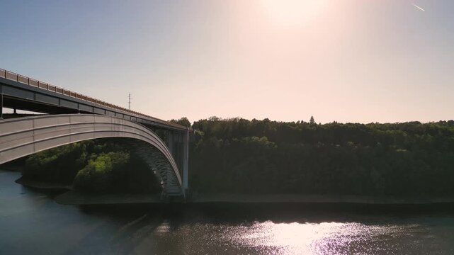 Aerial view of Zdakov Bridge spanning the Vltava River surrounded by lush forests in Orlik nad Vltavou, South Bohemian Region, Czechia.