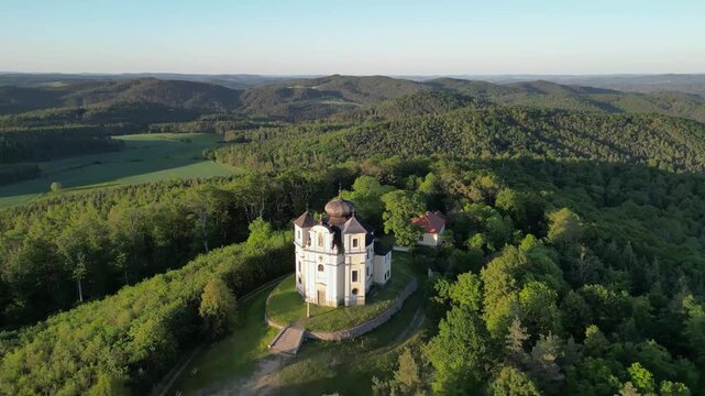 Aerial view of Makova hora church perched on a forested hill surrounded by lush greenery in Smolotely, Stredocesky kraj, Czechia.