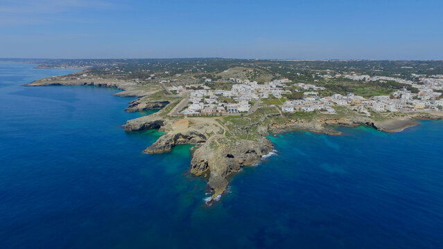 Aerial view of Santa Maria di Leuca featuring the rugged coastline, turquoise waters, and white buildings of the town in Santa Maria di Leuca, Puglia, Italy.