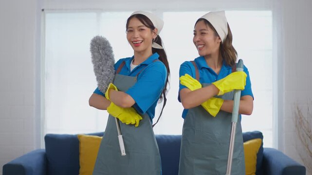 Cleaner woman glove uniform duster housekeeping smile apron teamwork service cheerful housekeepers holding mop rag in bright living room home interior