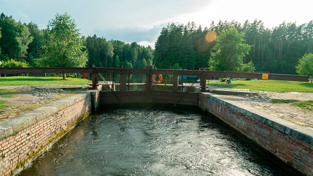Waterway lock in forested area during late afternoon light with flowing water and greenery around