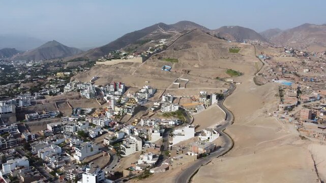 Aerial view of the wall of shame separating San Juan de Miraflores and Santiago de Surco districts, showing the contrast between urban development and hills in Lima, Lima Province, Peru.